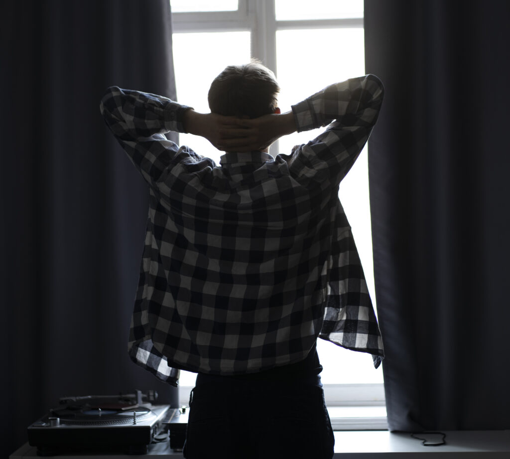 man looking out a window in dark background